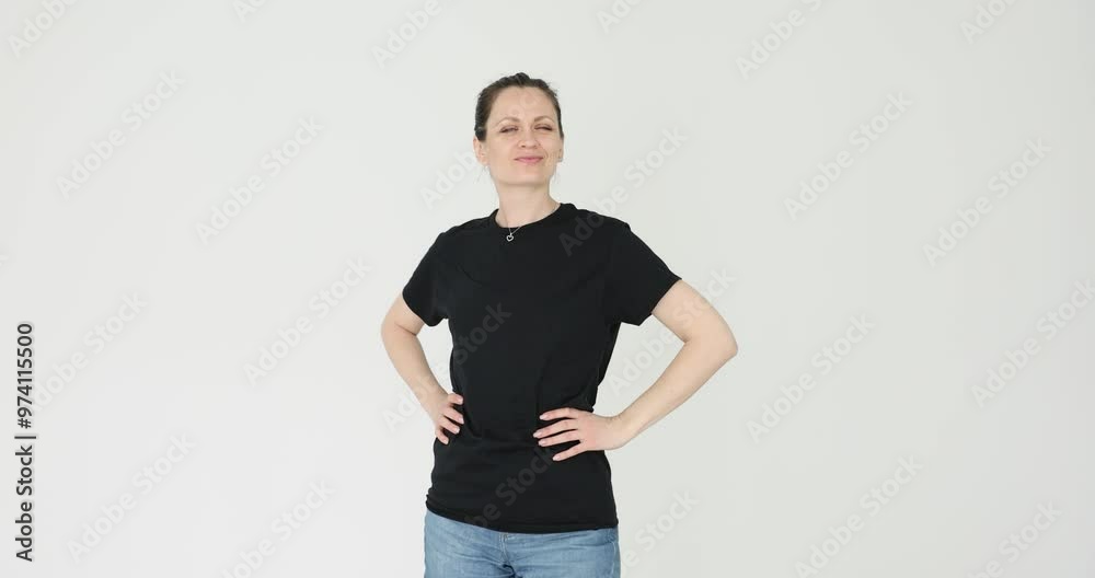 Attractive woman places hands on waist and poses for photo on white background. Pose of young female in black t-shirt exudes confidence and grace Attractive woman places hands on waist and poses for photo on white background. Pose of young female in black t-shirt exudes confidence and grace