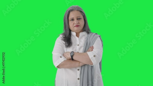 Confident Indian senior businesswoman standing crossed hands Green screen