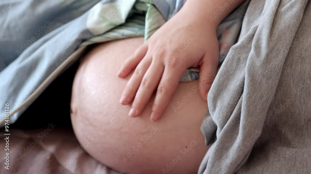 Close-up of a pregnant woman gently touching her belly before childbirth. The image captures the emotional connection and anticipation, highlighting the intimate and comforting moments before delivery