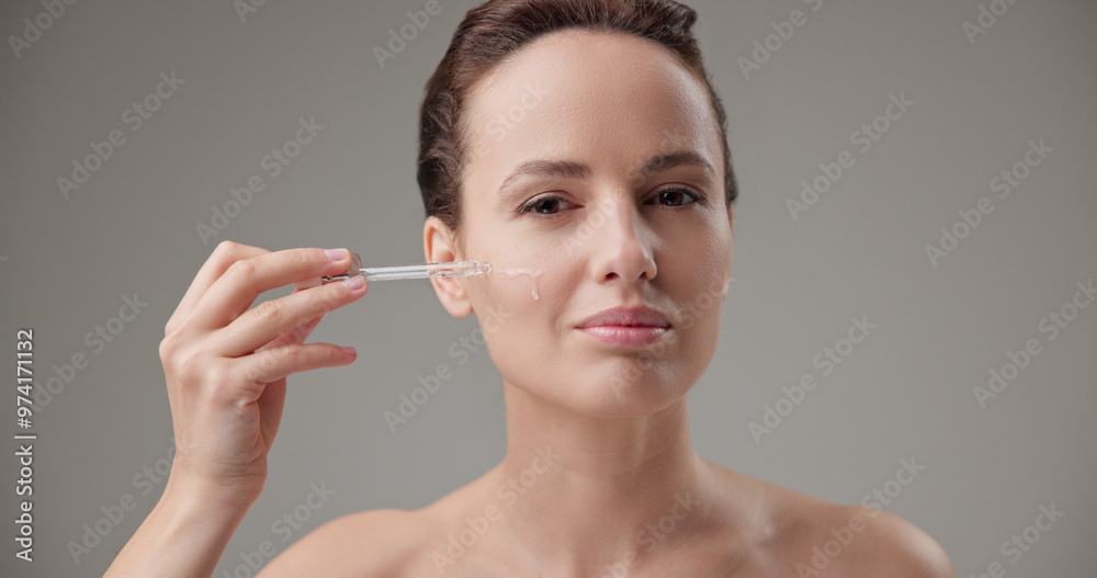 Beauty, health, cosmetics, anti-aging therapy and skin care concept - young beautiful brunette Caucasian woman applying cosmetic serum from a pipette for facial skin care Beauty, health, cosmetics, anti-aging therapy and skin care concept - young beautiful brunette Caucasian woman applying cosmetic serum from a pipette for facial skin care