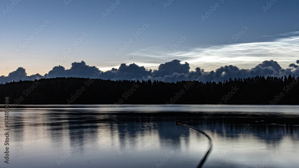 Obraz premium charming night landscape with silver clouds, silver clouds over the lake, dark forest silhouette in the background, mesospheric clouds