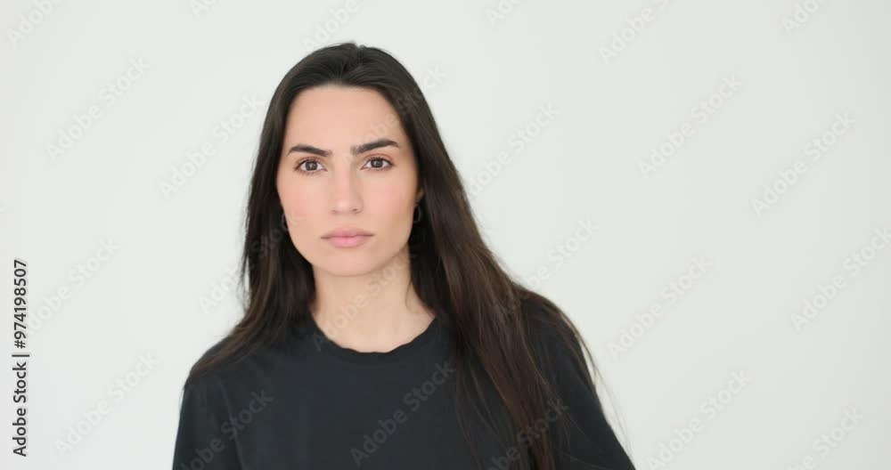 Curious brunette woman looks at camera placing face closer on white background. Attractive female model with loose hair studies data onscreen pov