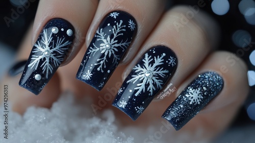 Close-up of a Hand with Dark Blue Nail Polish Decorated with White Snowflakes photo