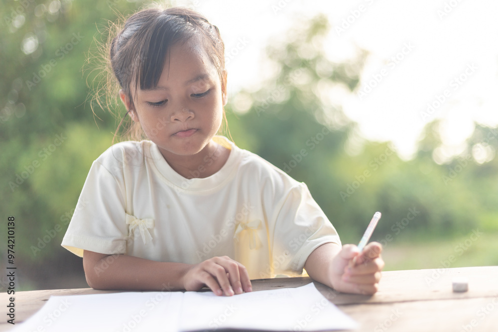 A young girl is sitting at a table writing in a notebook A young girl is sitting at a table writing in a notebook