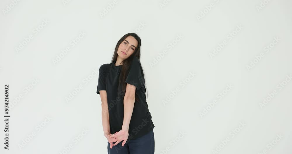Young woman in black outfit stretches arms clasping fingers on white background. Female model showcases commitment to fitness and healthy lifestyle Young woman in black outfit stretches arms clasping fingers on white background. Female model showcases commitment to fitness and healthy lifestyle