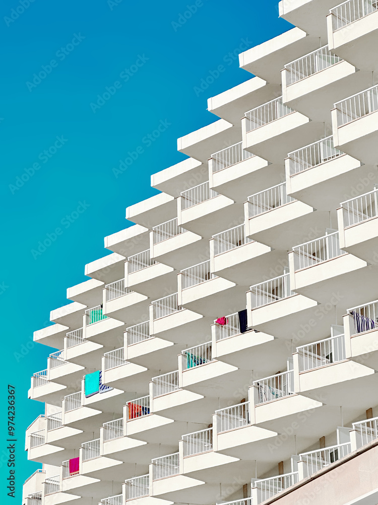 Naklejka premium Minimalist photo of resort hotel building with repeating patterns of windows and architectural elements and blue sky in the background