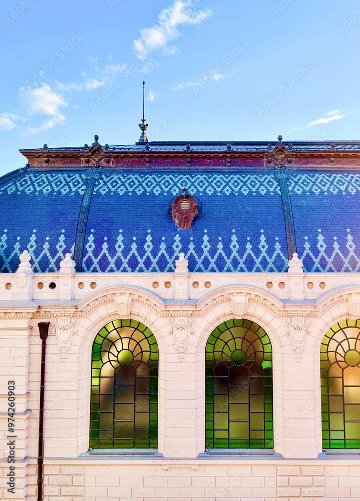 Naklejka premium Blue roof and green windows of old European historical palace made of white brick against blue sky with clouds