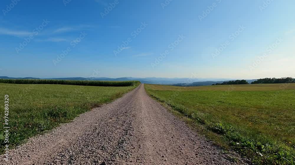 Riding forward on gravel dirt road along green agriculture fields and meadows Riding forward on gravel dirt road along green agriculture fields and meadows
