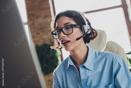 Photo of sweet charming lady assistant wear shirt eyeglasses headphones talking modern device indoors workplace workstation