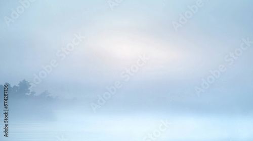 Misty landscape with soft fog over water at sunrise