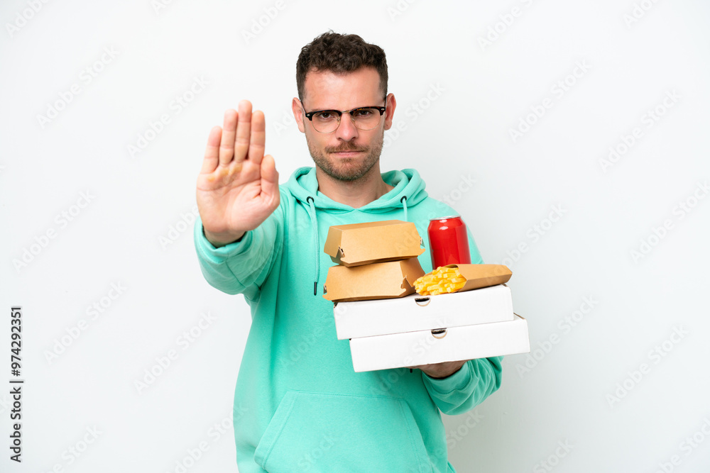 Young caucasian man holding fast food isolated on white background making stop gesture Young caucasian man holding fast food isolated on white background making stop gesture