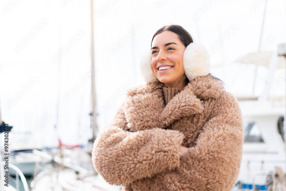 Young woman wearing winter muffs at outdoors happy and smiling