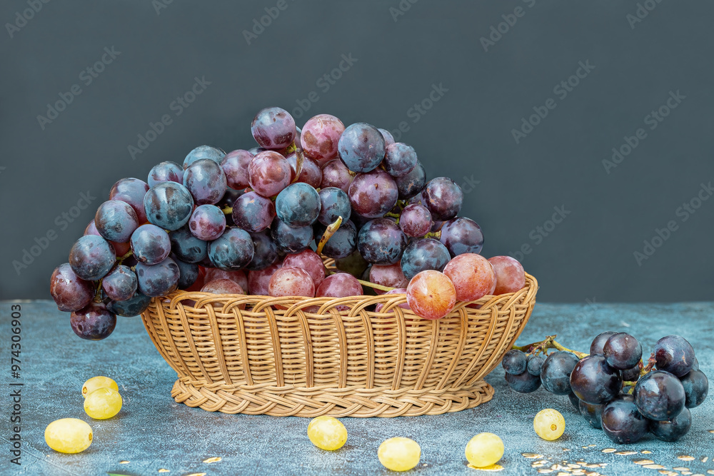 Black grapes in a wicker basket on a table.