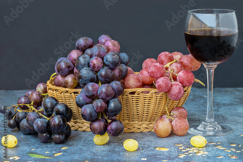 Obraz na płótnie Black grapes on a table, red grapes in a basket and a glass of red wine on the table w salonie