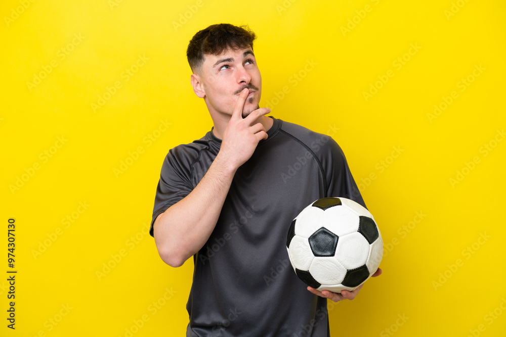 Young football player man isolated on yellow background having doubts while looking up Young football player man isolated on yellow background having doubts while looking up
