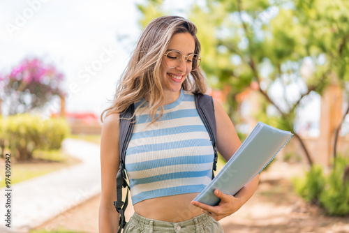 Young pretty student woman at outdoors with happy expression