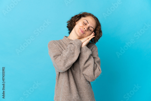 Young English woman isolated on blue background making sleep gesture in dorable expression photo