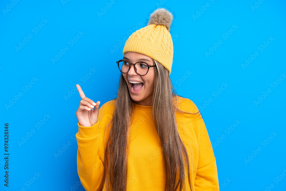 Young caucasian woman wearing winter clothes isolated on blue background intending to realizes the solution while lifting a finger up Young caucasian woman wearing winter clothes isolated on blue background intending to realizes the solution while lifting a finger up