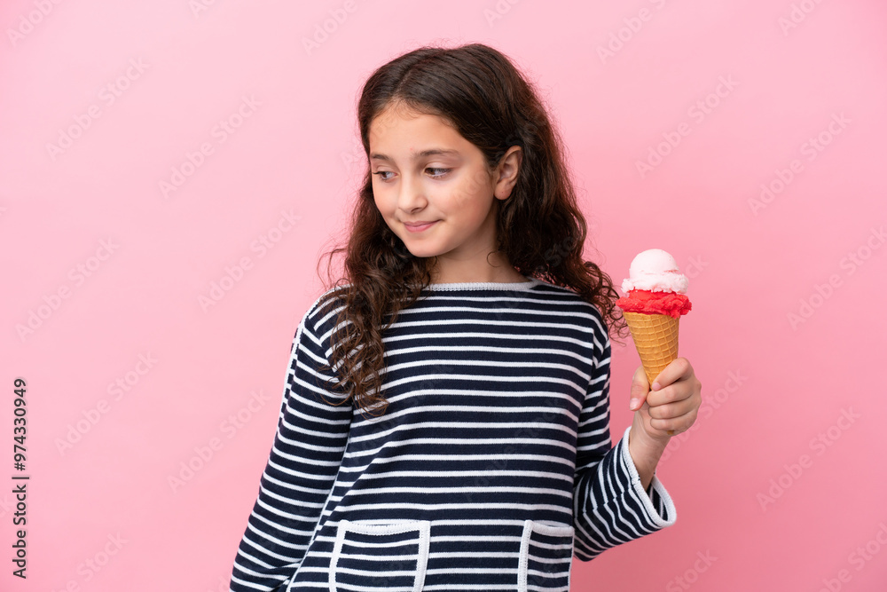Little caucasian girl holding an ice cream isolated on pink background looking to the side and smiling Little caucasian girl holding an ice cream isolated on pink background looking to the side and smiling