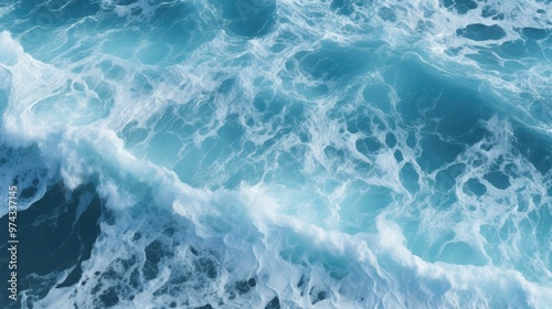 A stunning aerial view of the ocean with whitecaps and foamy waves. The water is a beautiful blue, and the sun is shining brightly.