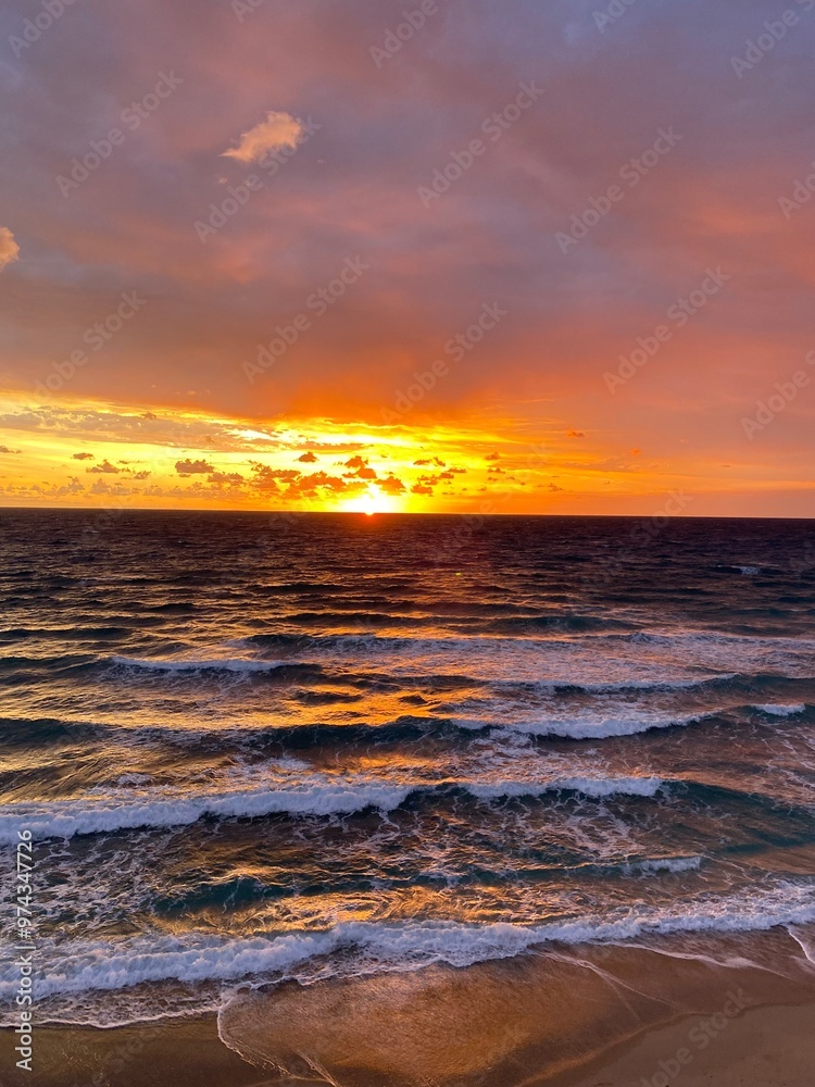 Obraz premium Fiery pre-sunrise peaking through the clouds lighting up the ocean