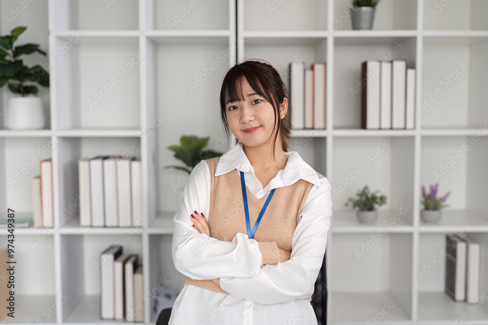 Confident Young Female Office Worker Posing in Modern Workspace with Shelves and Plants in Background Confident Young Female Office Worker Posing in Modern Workspace with Shelves and Plants in Background