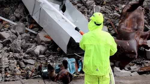 Worker hosing down dusty demolition in city