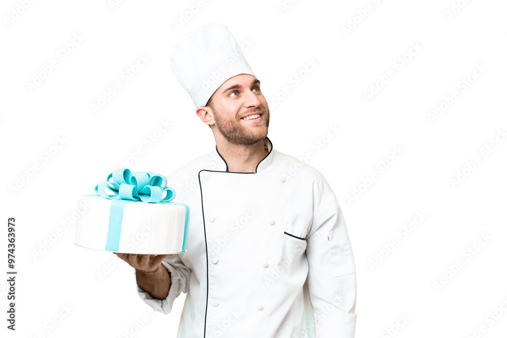 Young handsome blonde man with a big cake over isolated chroma key background looking up while smiling Young handsome blonde man with a big cake over isolated chroma key background looking up while smiling