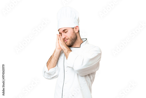 Young blonde man Chef over isolated chroma key background making sleep gesture in dorable expression photo