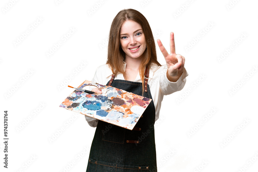 Young artist woman holding a palette over isolated chroma key background smiling and showing victory sign Young artist woman holding a palette over isolated chroma key background smiling and showing victory sign