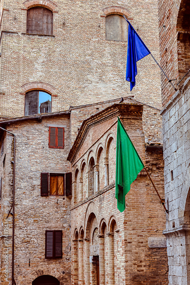 Medieval architecture of San Gimignano, Tuscany with colorful flags adorning historic buildings