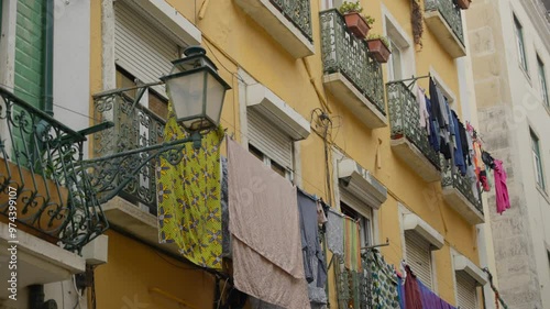 Laundry and clothes hanging out to dry in the sun on balconies in Portugal. European city narrow streets with local residents drying clothes outside. Colorful buildings in cute peaceful neighborhood