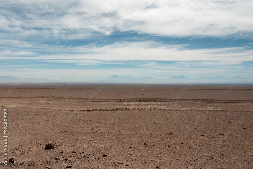 Arid landscape dominating the view with its immense expanse of dry earth and rocks, stretching towards a distant mountain range shrouded in a soft haze Arid landscape dominating the view with its immense expanse of dry earth and rocks, stretching towards a distant mountain range shrouded in a soft haze