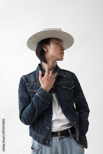 Vertical portrait of confident young Asian man wearing hat posing indoor over white background. 