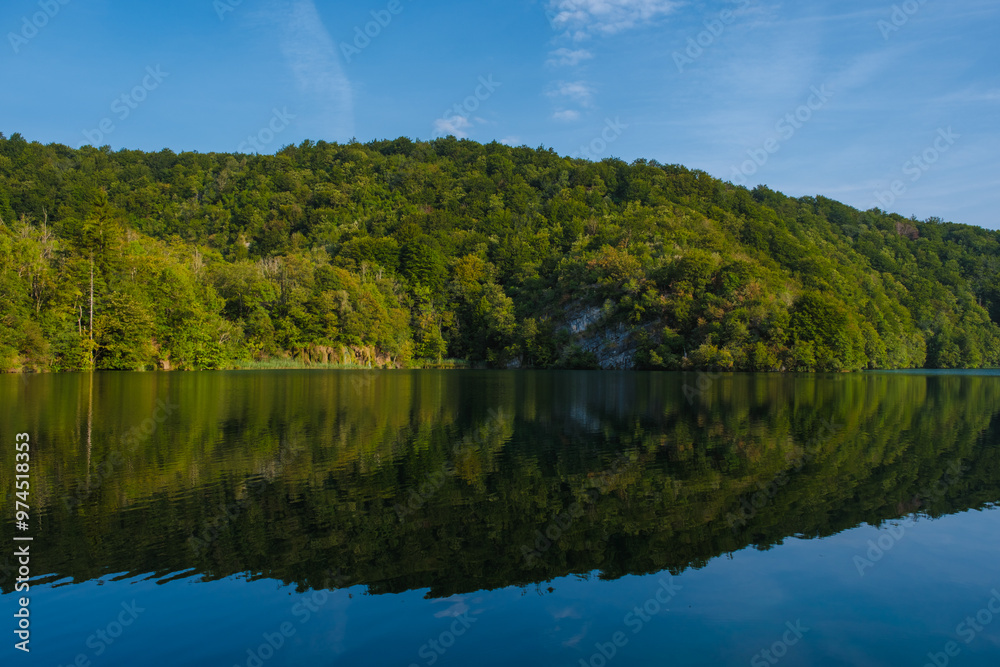 A peaceful morning unfolds at Plitvice Lakes, where lush greenery surrounds still waters, creating stunning reflections A peaceful morning unfolds at Plitvice Lakes, where lush greenery surrounds still waters, creating stunning reflections