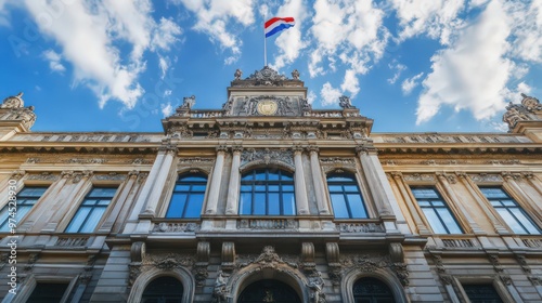 The facade of a historic government building with traditional architecture, ornate details, and a large flagpole displaying the national flag