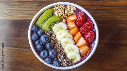 Delicious acai bowl topped with fresh fruits and granola on a wooden table