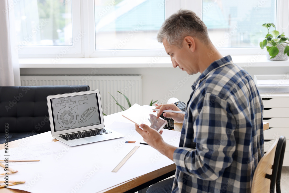 Obraz premium Architect making digital engineering drawing on tablet at table in office