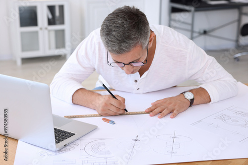 Architect making engineering drawing at wooden table in office