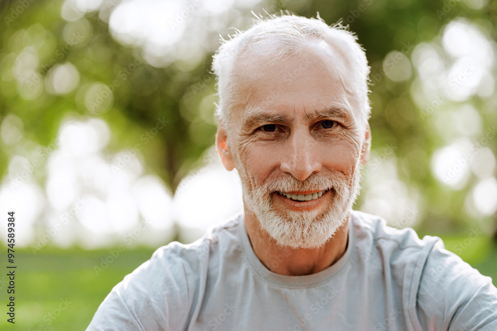 Portrait of happy senior man smiling while enjoying sunny day at the park, looking at camera Portrait of happy senior man smiling while enjoying sunny day at the park, looking at camera