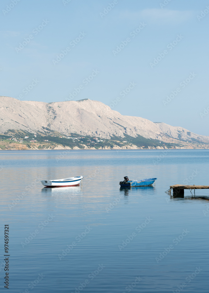 Two boats moored at sea near dock, mountainous island in background Two boats moored at sea near dock, mountainous island in background