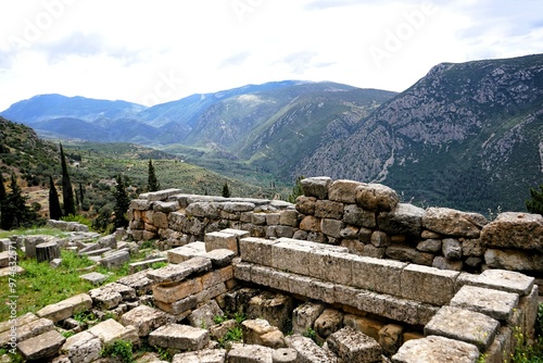 Ancient Greek ruins of the temple complex of the Oracle of Delphi in Greece with a breathtaking view of the panorama of the Pleistos River valley on a sunny summer's day  photo