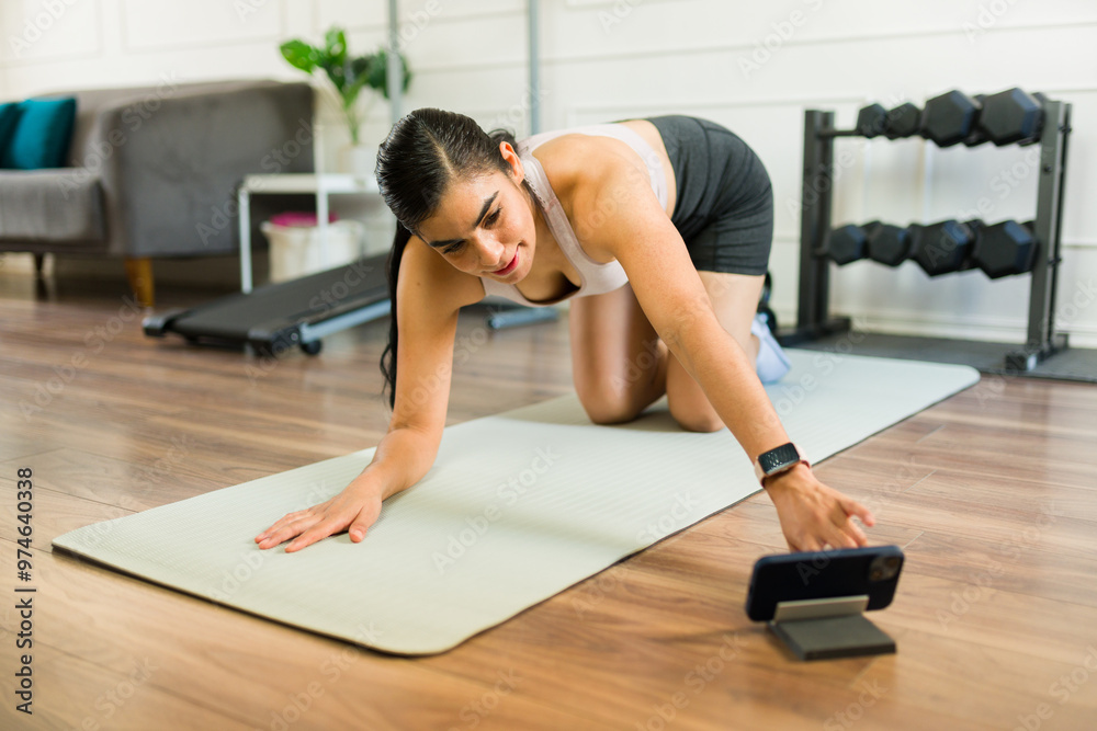 Athletic woman using a fitness app on her smartphone and following an online workout routine at home Athletic woman using a fitness app on her smartphone and following an online workout routine at home