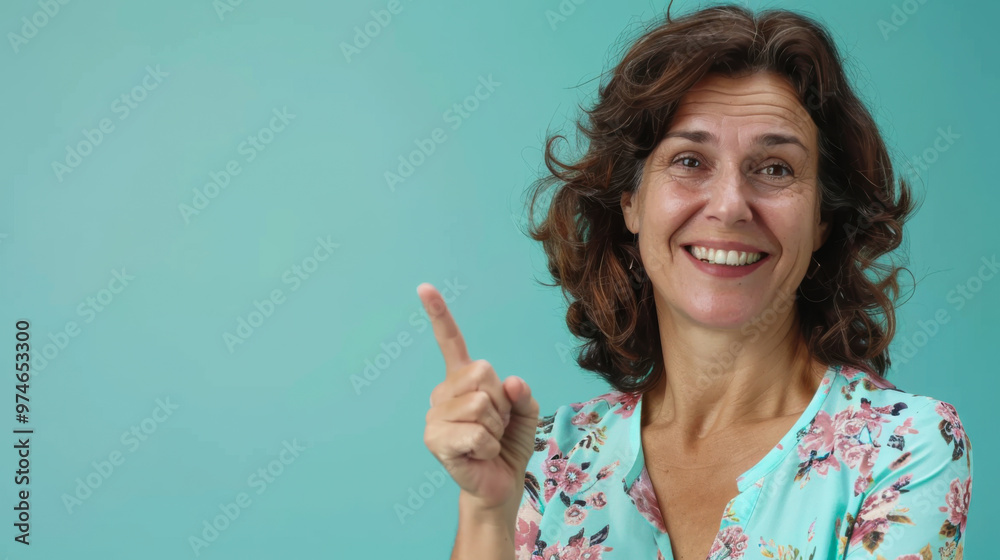 Smiling woman with long wavy hair points to the right against a light blue background in a casual setting Smiling woman with long wavy hair points to the right against a light blue background in a casual setting