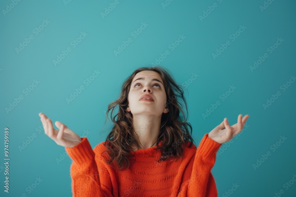 A young woman with long brown hair looks up with a curious and hopeful expression on her face, against a bright blue background.
