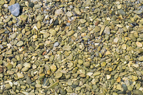 Photo background texture, rocky river bottom with clear transparent water on the shallows.