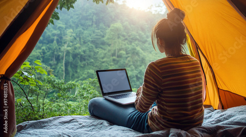 person working on laptop in tent.