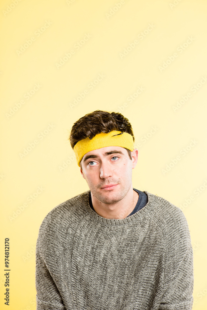 Bored man, headband and face with hair, thinking or lazy expression on a yellow studio background. Young, male person or tired model with emotion or sweatband on forehead for style on mockup space Bored man, headband and face with hair, thinking or lazy expression on a yellow studio background. Young, male person or tired model with emotion or sweatband on forehead for style on mockup space