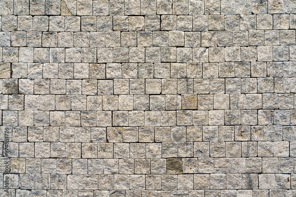 Fototapeta premium A Weathered Granite Cobblestones background in Earthy Tones. Features a rough texture in beige and gray. Ideal for retro designs, websites, brochures, or as a textured backdrop for text placement.