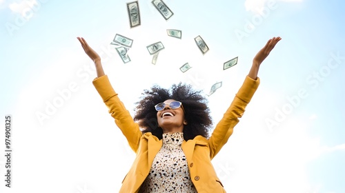 A young woman with curly hair smiles as she reaches up for money falling from the sky.